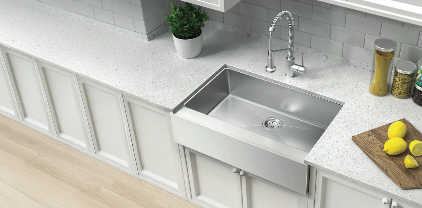 Stainless-steel farmhouse sink with a tall faucet in a bright white kitchen